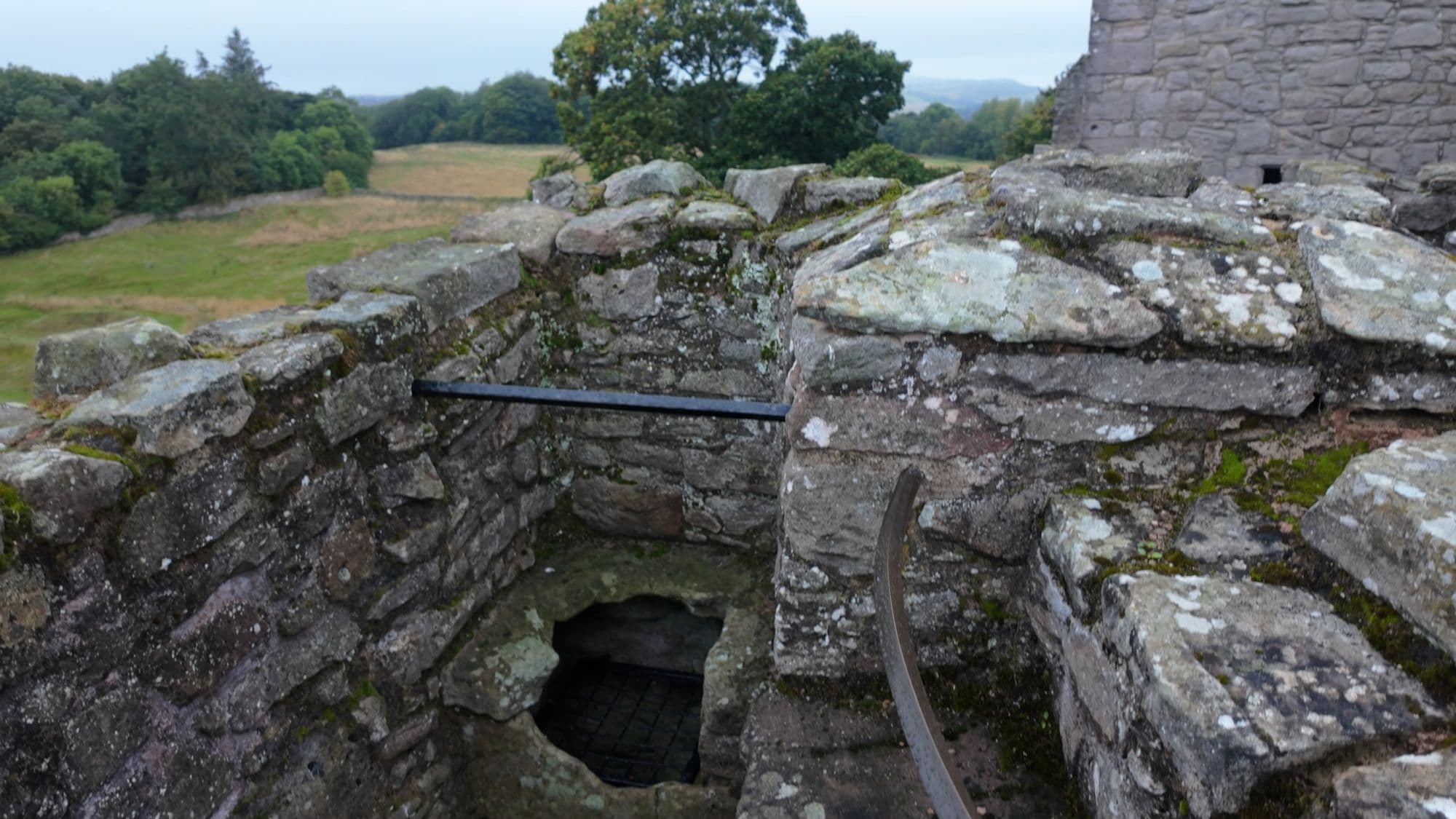 An open latrine shaft at the roof level, dropping straight down through the thickness of the wall
