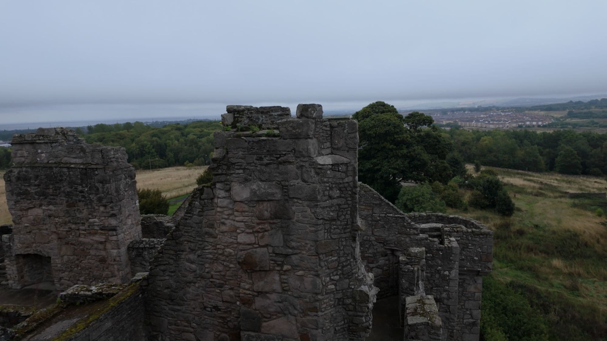 Ruined upper walls of the tower house from the roof, with Edinburgh's southern suburbs and the Firth of Forth beyond