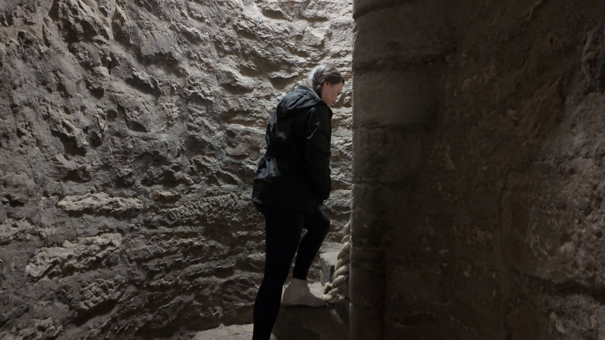 My sister climbing a steep, narrow stair cut through the rock inside the castle
