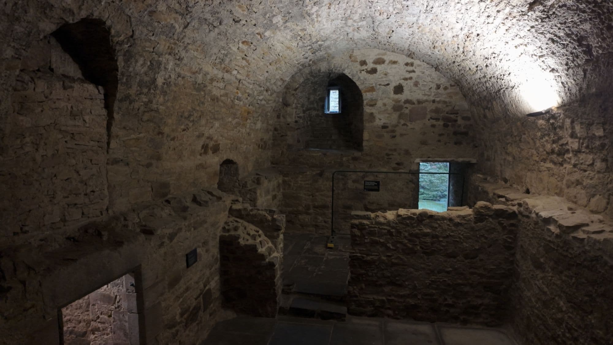 One of Craigmillar's vaulted cellars, rough stone walls and a single small window at the far end