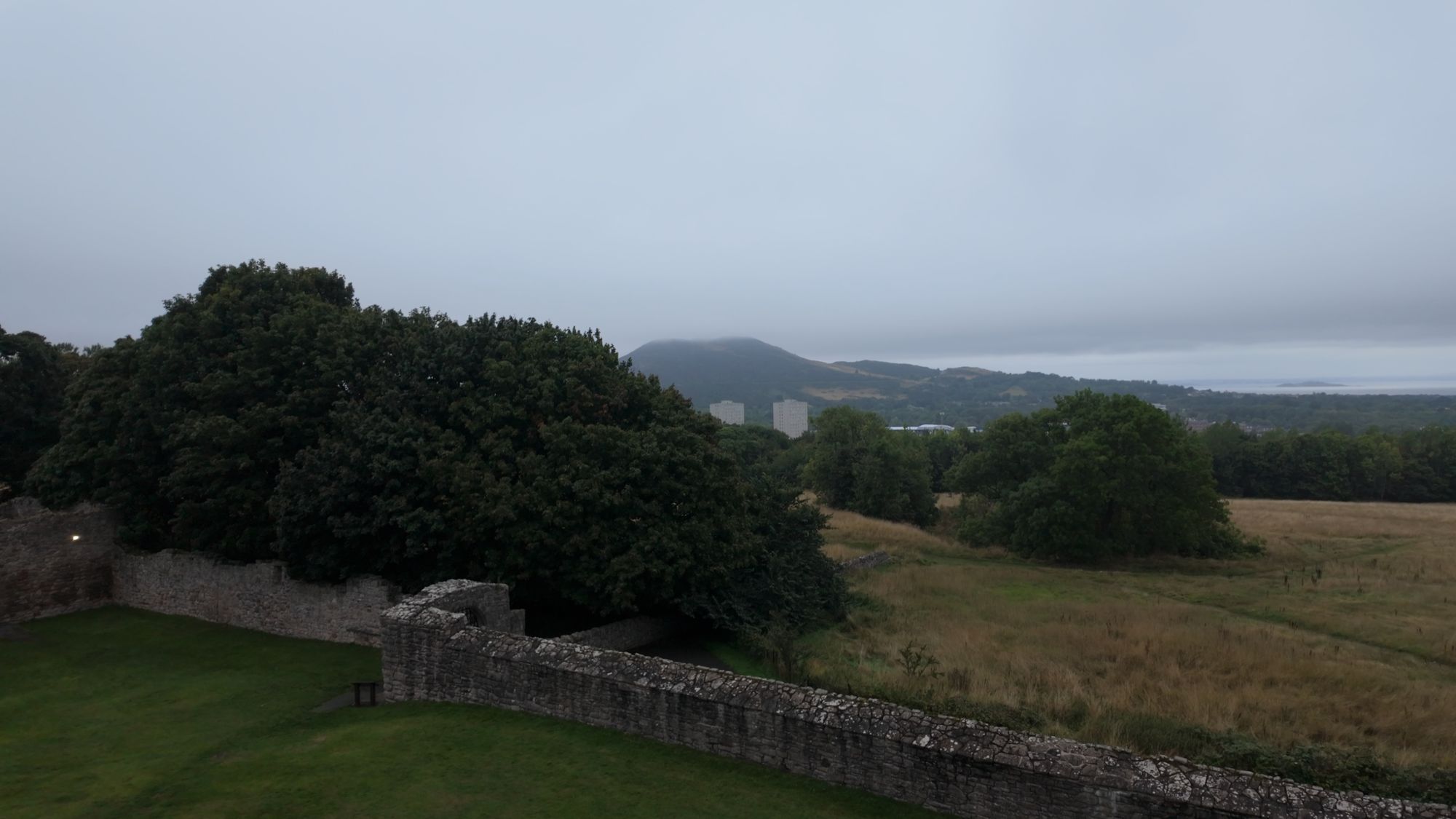 The view north from the Craigmillar tower roof: the castle wall and trees in the foreground, Arthur's Seat on the skyline