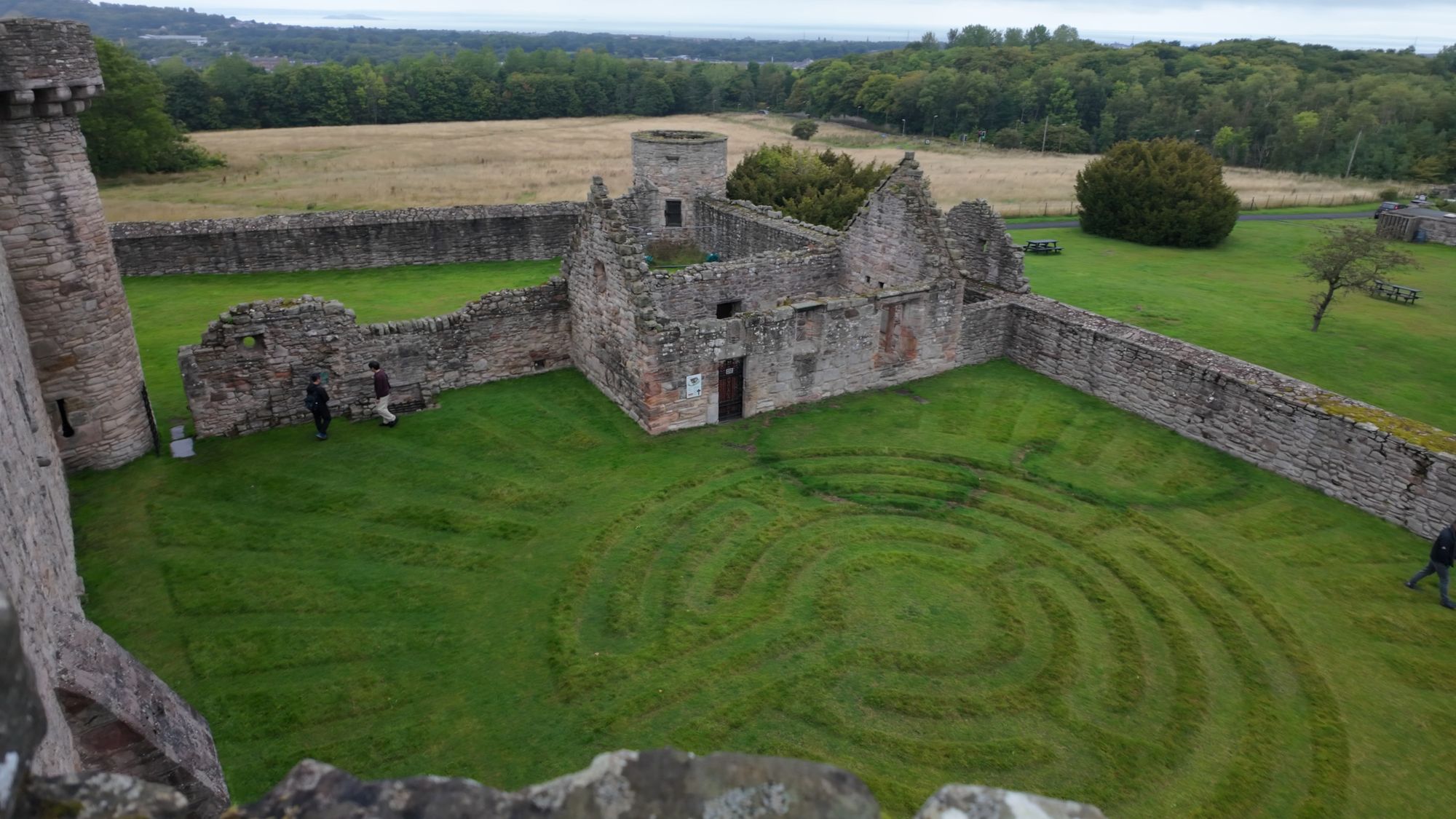 The outer courtyard from the tower roof: the ruined chapel and walled grounds, with a spiral pattern mown into the lawn