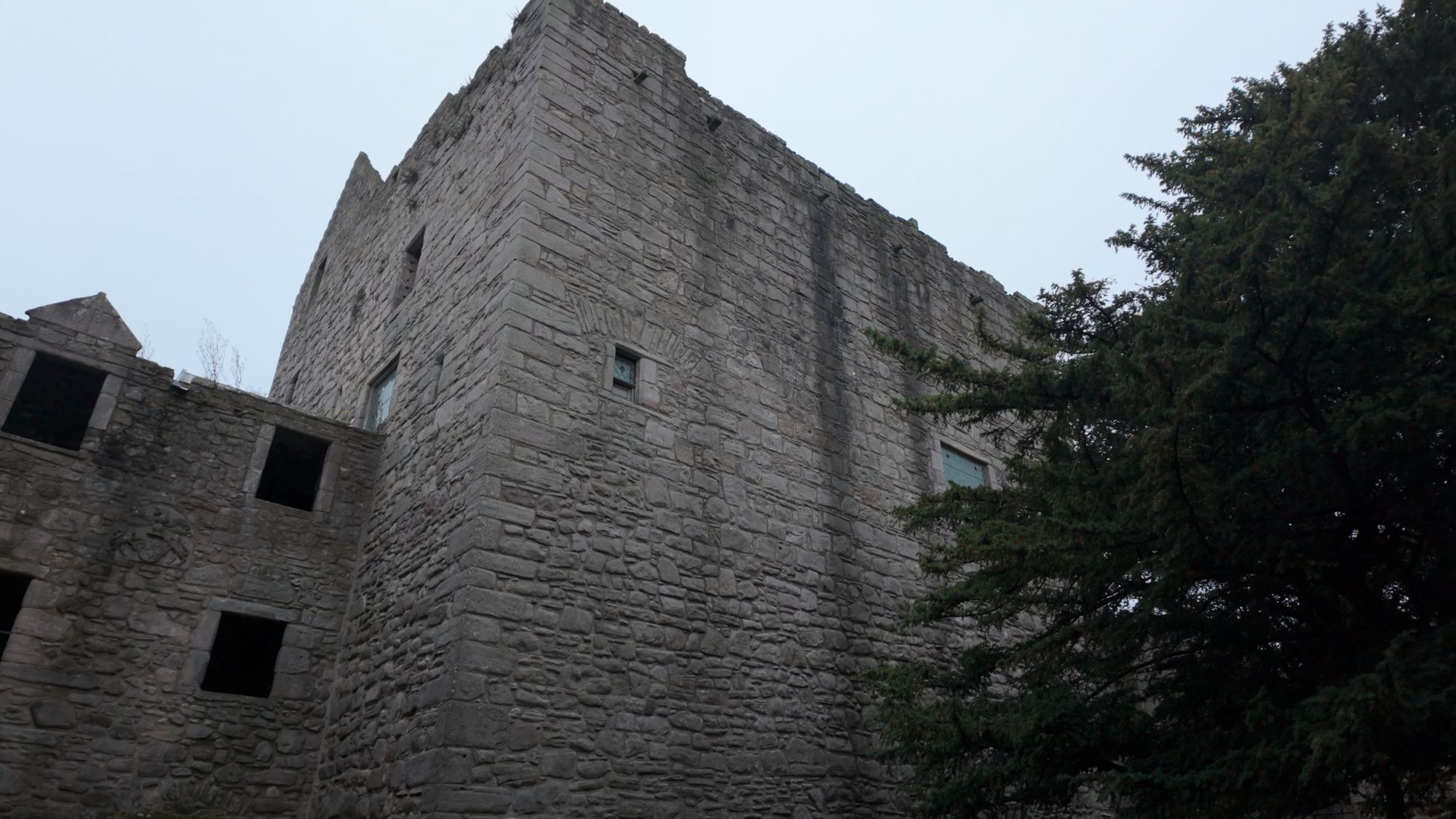 Looking up at the tower house from the inner courtyard, its sheer gray walls pierced by a few small windows