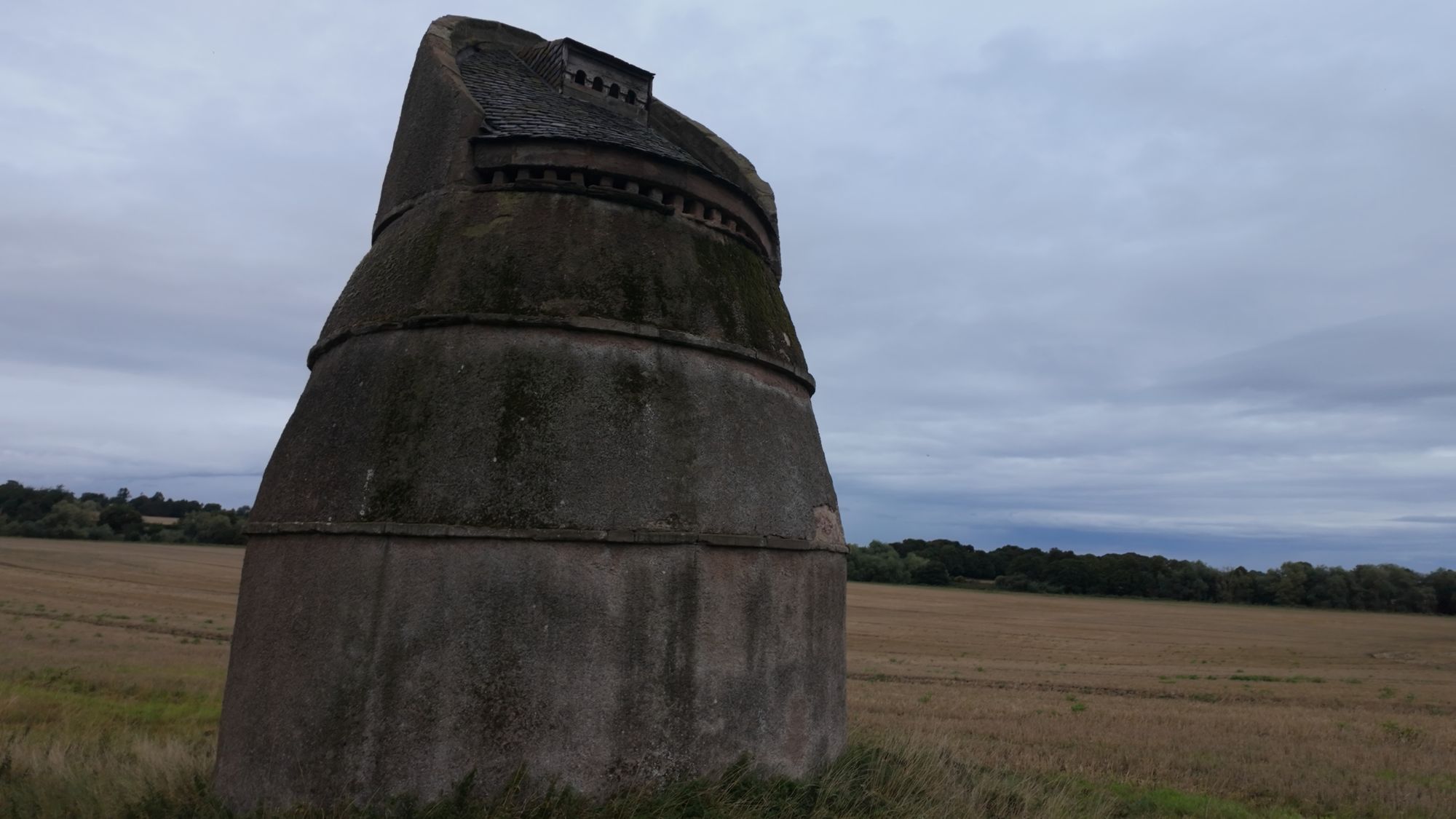 Closer on the doocot, its sloping horseshoe-shaped top and the stone ledge running around the middle