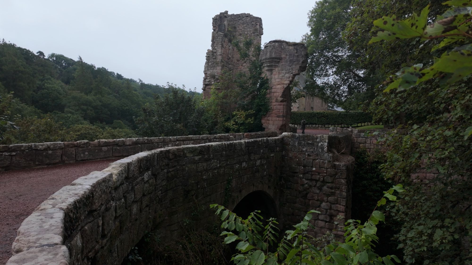 The high stone bridge over the gorge to Rosslyn Castle, a ruined tower fragment standing on the far side among the trees