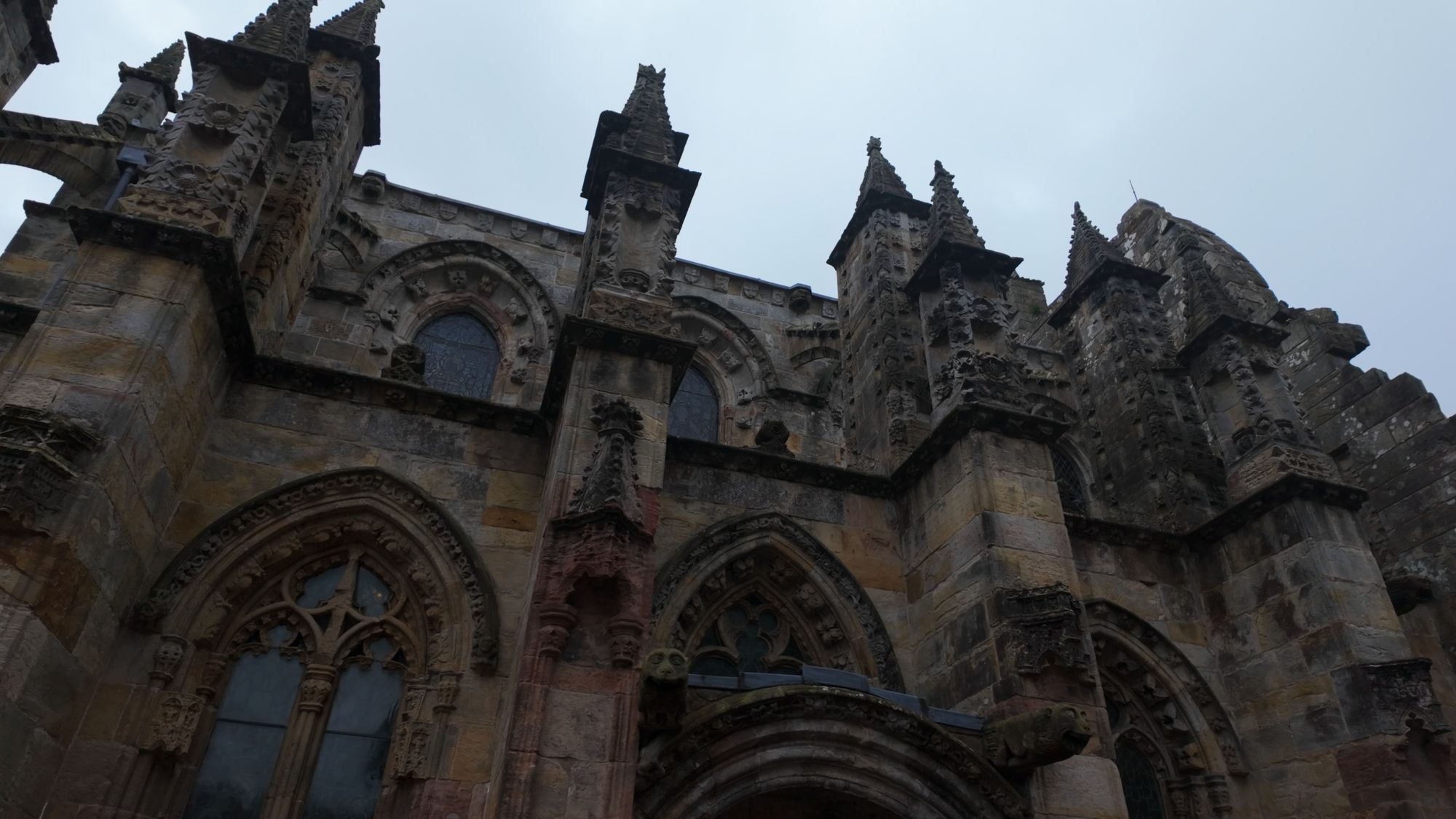 The crowded upper walls of Rosslyn Chapel — flying buttresses, pinnacles and carved niches packed against each other