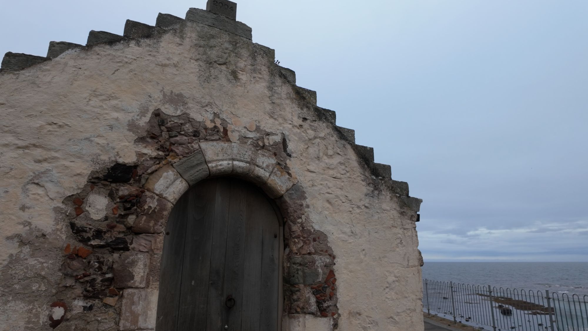 A crowstepped gable of the old kirk with a blocked arch and an old wooden door