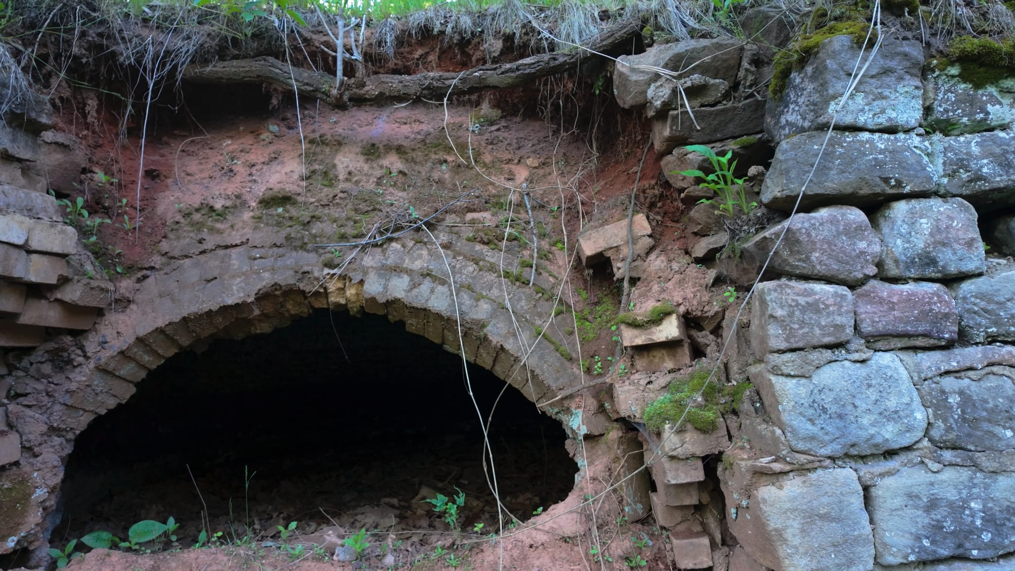 A partially collapsed oven being slowly swallowed by the hillside
