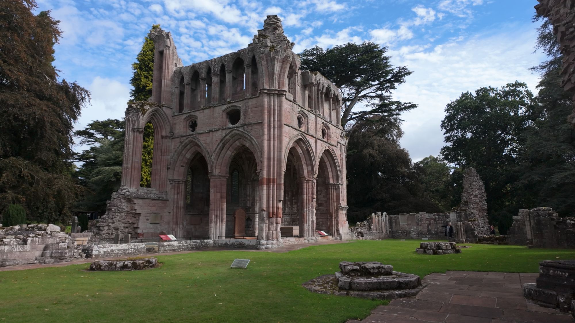 Dryburgh Abbey in its wooded setting, the tall gable of the church framed by overhanging branches