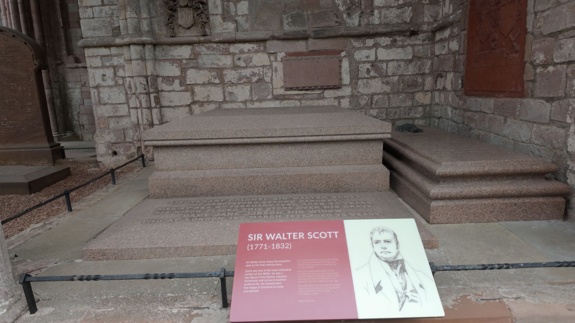 Sir Walter Scott's polished red granite tomb in the north transept, with an information panel beside it