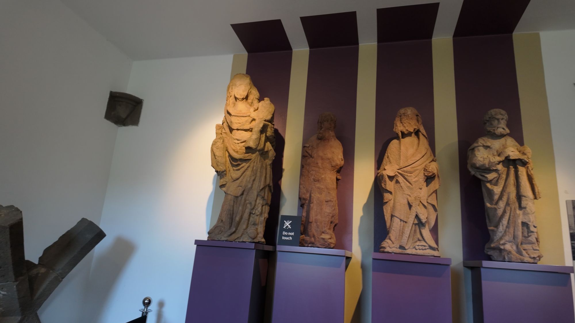 Four weathered medieval statues of saints from the abbey, displayed on plinths in the Commendator's House Museum