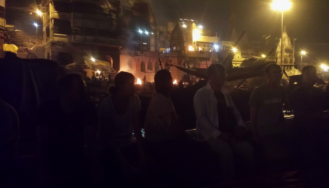 The ghats at sunset — smoke from Manikarnika visible against the sky