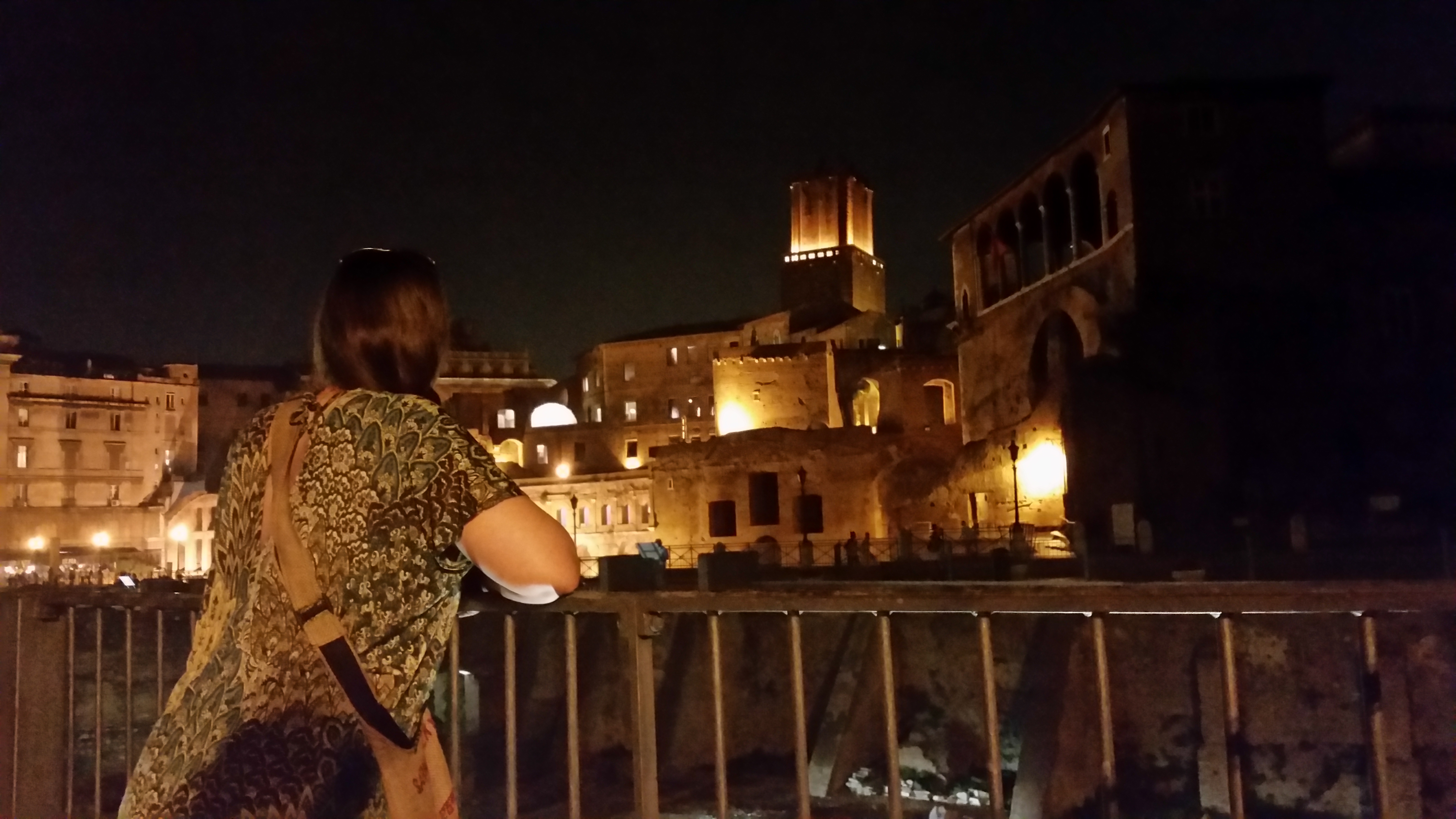 My sister among floodlit Roman ruins at night in Rome