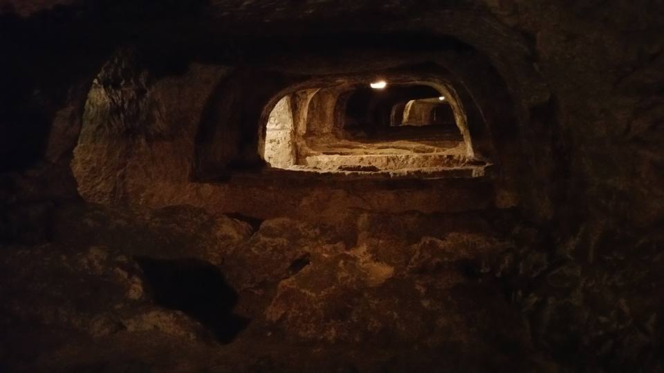 Endless rock-cut tombs receding into the dark at St. Paul's Catacombs